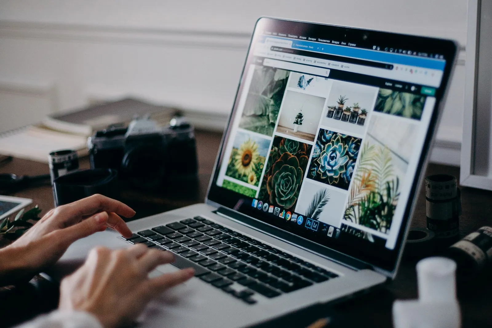 Handen op een laptop met een website open, op een houten tafel