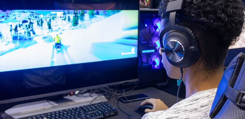 Gamer met koptelefoon achter een pc
